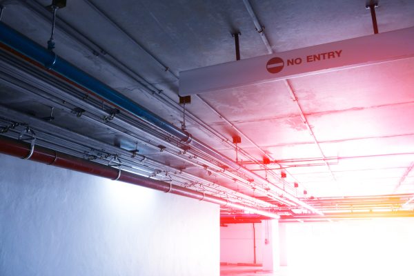 Sanitary system pipes and electrical cables installed under flat slab reinforced concrete structure in building.Ventilation pipes in Underground Parking and no entry sign